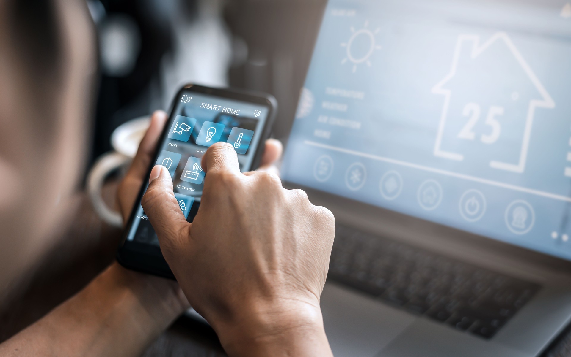 Young man using smart phone and notebook computer while working from home; interior of man using smart phone; man at work utilizing technology